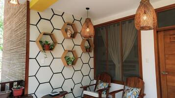 A room with hexagonal wall patterns, wooden chairs with cushions, and hanging wicker lamps.