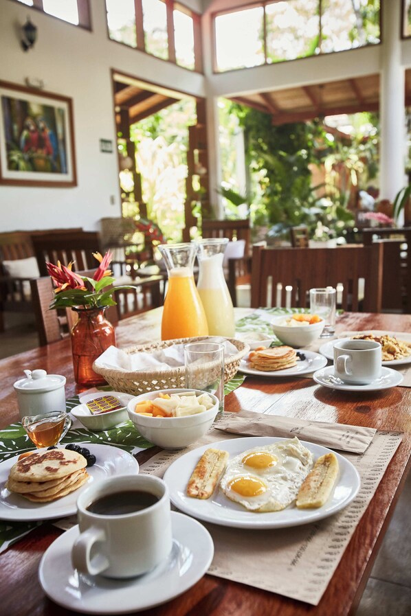 A breakfast table with plates of food, a coffee cup, and a pitcher of orange juice. - Villa Lu Amazon Lodge (Tarapoto)