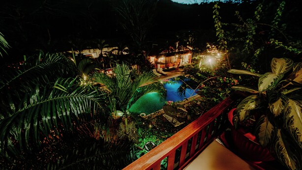 A nighttime view of a resort with a swimming pool surrounded by lush vegetation and a wooden deck. - Villa Lu Amazon Lodge (Tarapoto)