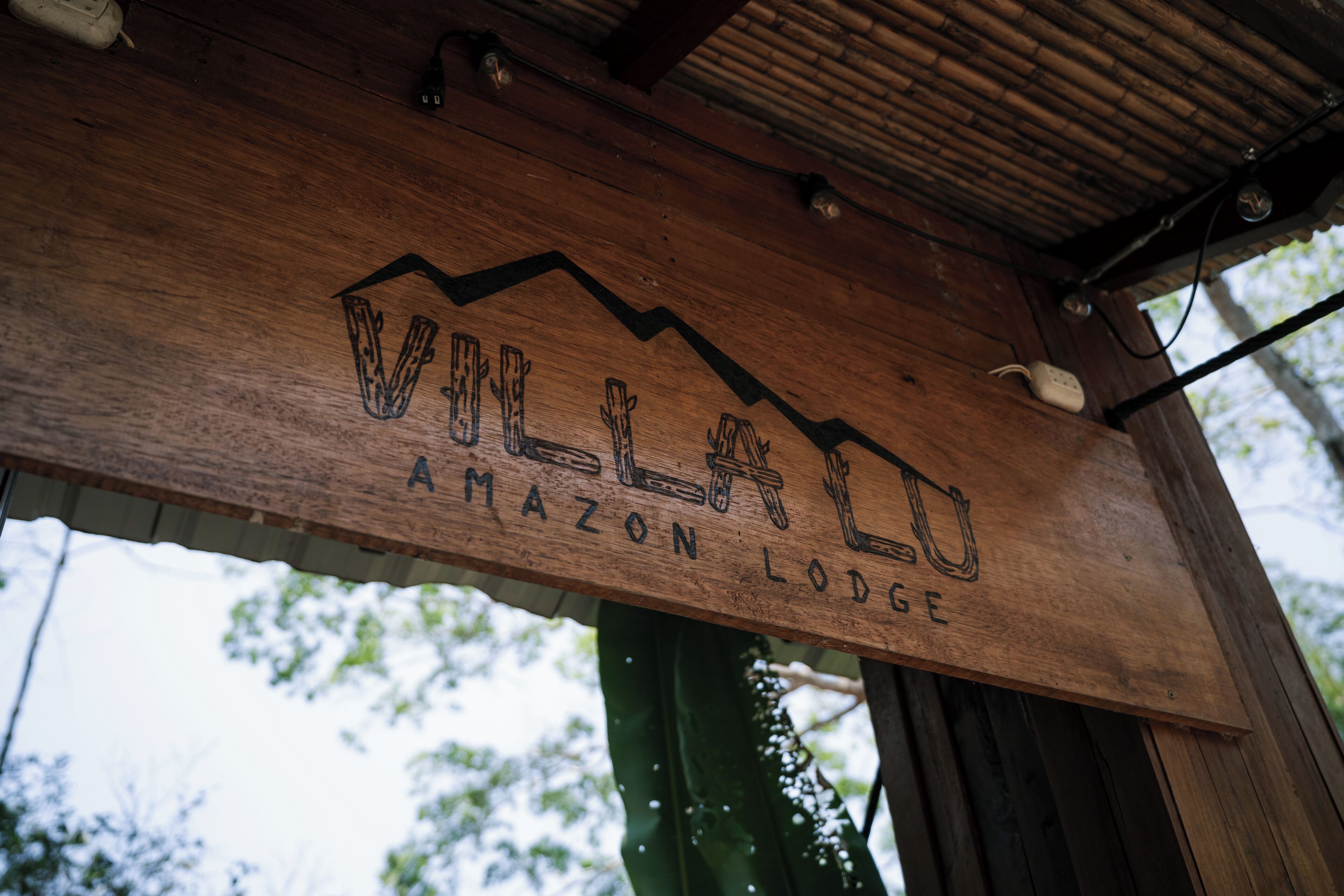 A wooden sign with the text "VILLADO AMAZON LODGE".