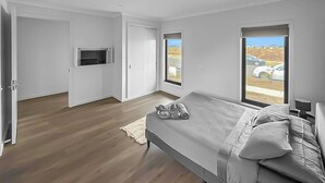 A bedroom with a bed, a TV, and a view of parked cars through a window. - 3BR Home Near Werribee Plaza w/ Free Parking + Free Wifi (Mambourin)