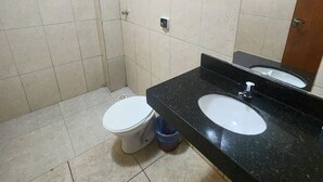 Ein Badezimmer mit Toilette, Waschbecken, Spiegel und Dusche.