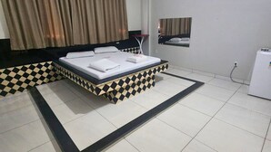 Ein Hotelzimmer mit einem Bett, einem kleinen Tisch, einem Spiegel und einem Kühlschrank.