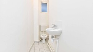 A small, white bathroom with a toilet, a window, and a sink. - Charming Flat -2br/6p- Montorgueil (Paris)