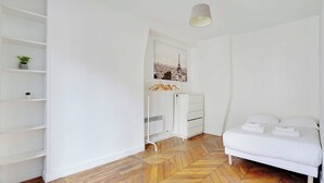 A bedroom with a bed, white wardrobe, and shelves with plants. - Charming Flat -2br/6p- Montorgueil (Paris)