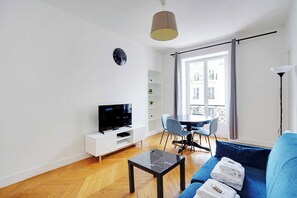 Una sala de estar moderna con sofá, televisor y comedor.