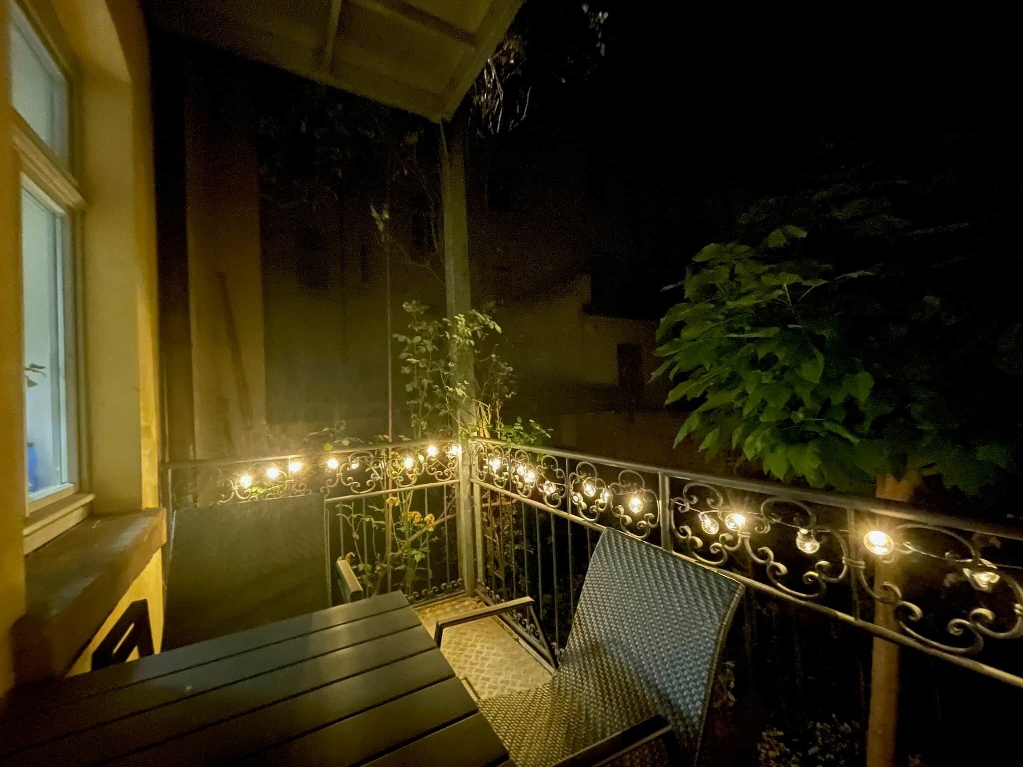 Ein Balkon mit Metallgeländer, einer Holzbank und einem Stuhl.