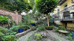Un jardin avec un mur en briques, des plantes en pot et un chemin pavé de pierres.