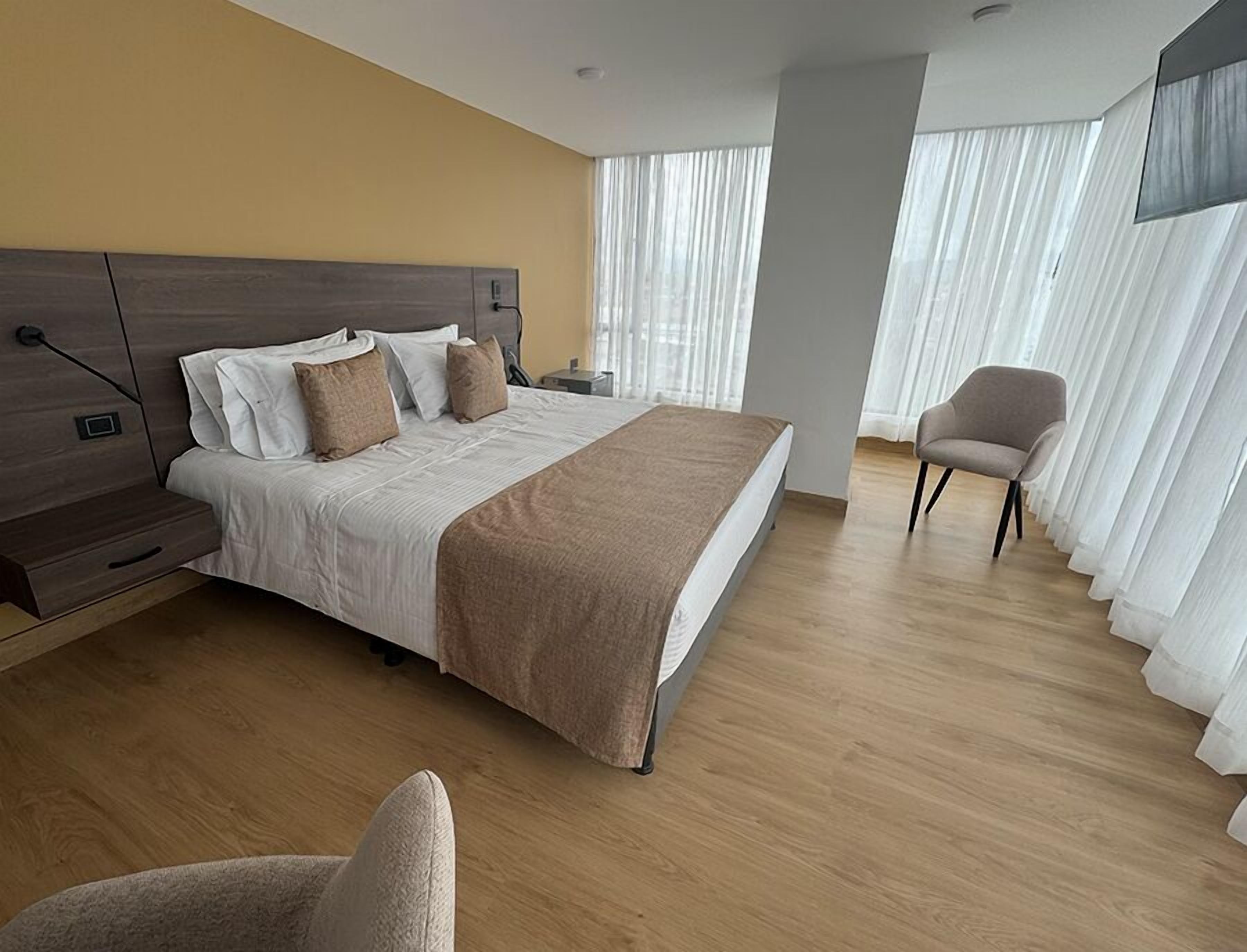 Et moderne hotelværelse med en stor seng, et natbord, en stol og et fjernsyn.