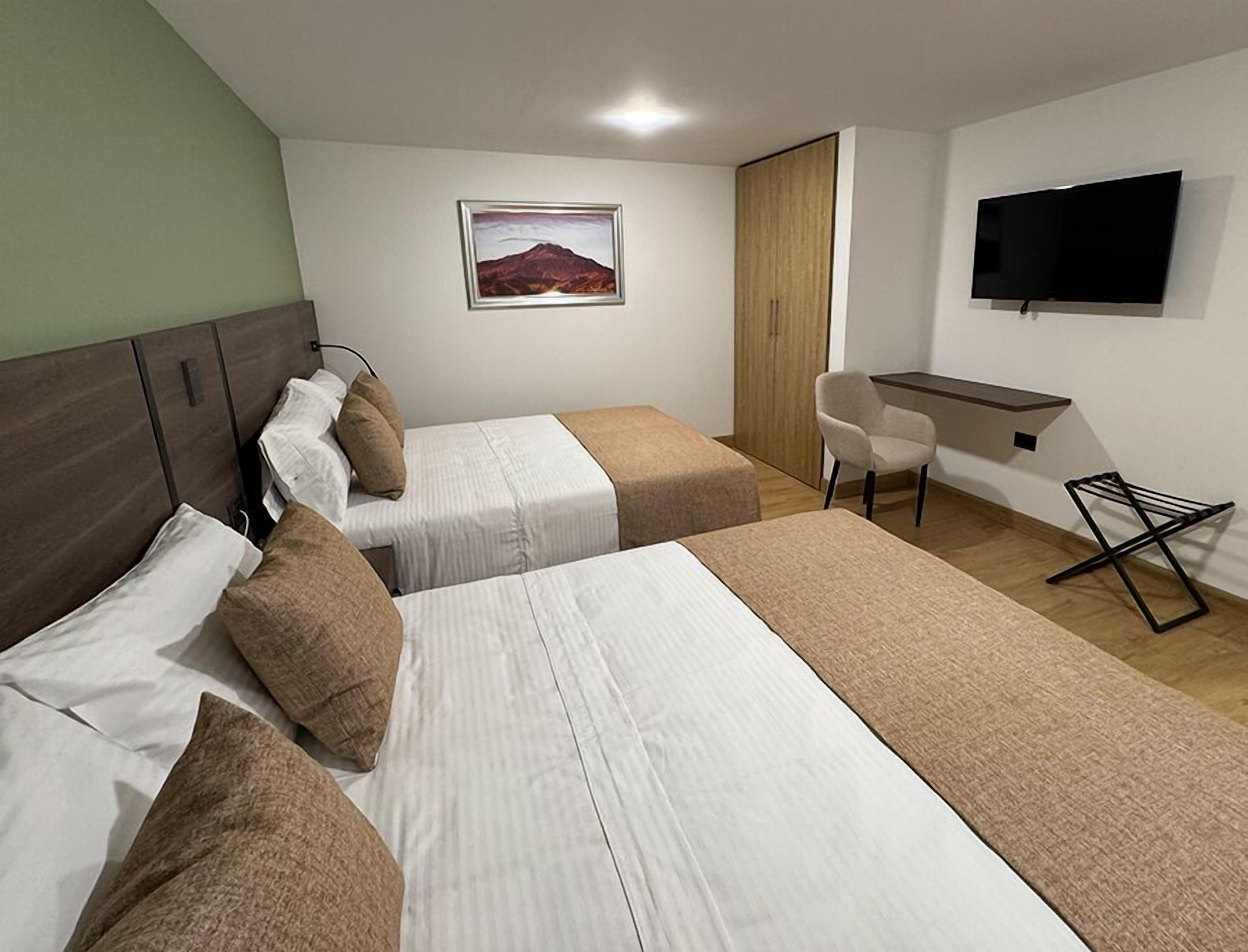 A hotel room with two beds, a desk, a chair, a TV, and a painting on the wall.