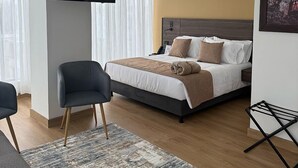 A modern hotel room with a bed, a chair, a TV, and a painting on the wall. - Entrenevados Hotel (Ipiales)
