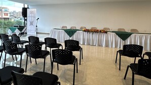 A conference room with a long table, black chairs, and a banner. - Entrenevados Hotel (Ipiales)