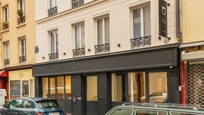 Un edificio de varios pisos con balcones, un escaparate y coches aparcados.