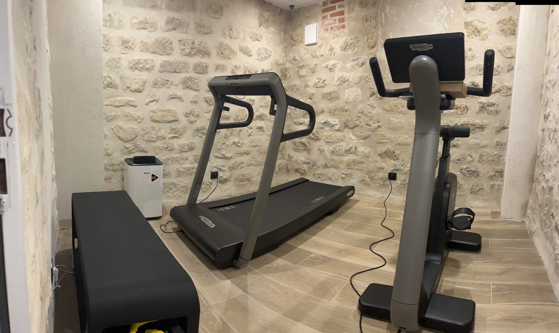 A home gym with a treadmill, elliptical, and bench.