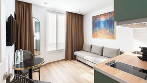 Una habitación de hotel moderna con sofá, mesa de comedor y kitchenette.