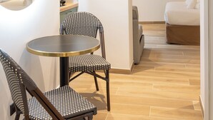 Un hotel moderno con una mesa de comedor redonda, dos sillas, un sofá, un espejo grande y un cuadro de flores en la pared.