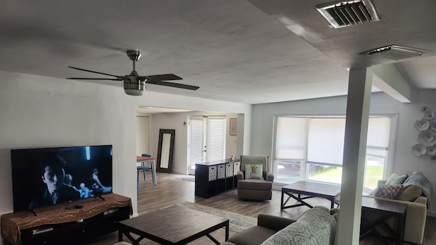 A living room with a television, sofa, coffee table, and a ceiling fan.