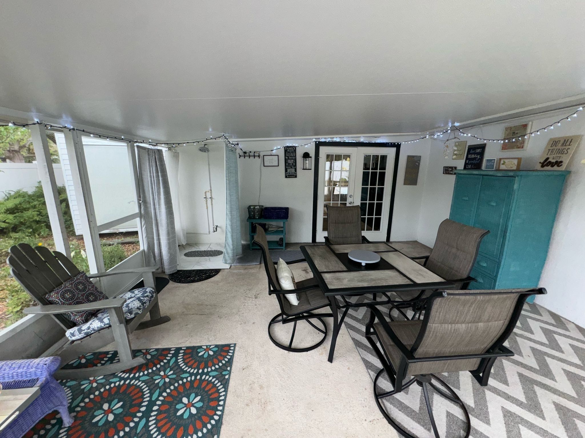 A covered patio area with a table and chairs, a small seating area with a bench, and a door leading to an outdoor space.