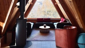 A cozy attic room with a large window, a wood-burning stove, and comfortable seating. - Très Grand Chalet Pointu sur les Pistes aux Arcs, 7 bedrooms and sauna (Bourg-Saint-Maurice)