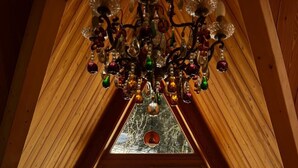 A cozy attic room with a wooden sloped ceiling, a chandelier, a large window with a view of a snowy landscape, and a wooden table with chairs. - Très Grand Chalet Pointu sur les Pistes aux Arcs, 7 bedrooms and sauna (Bourg-Saint-Maurice)