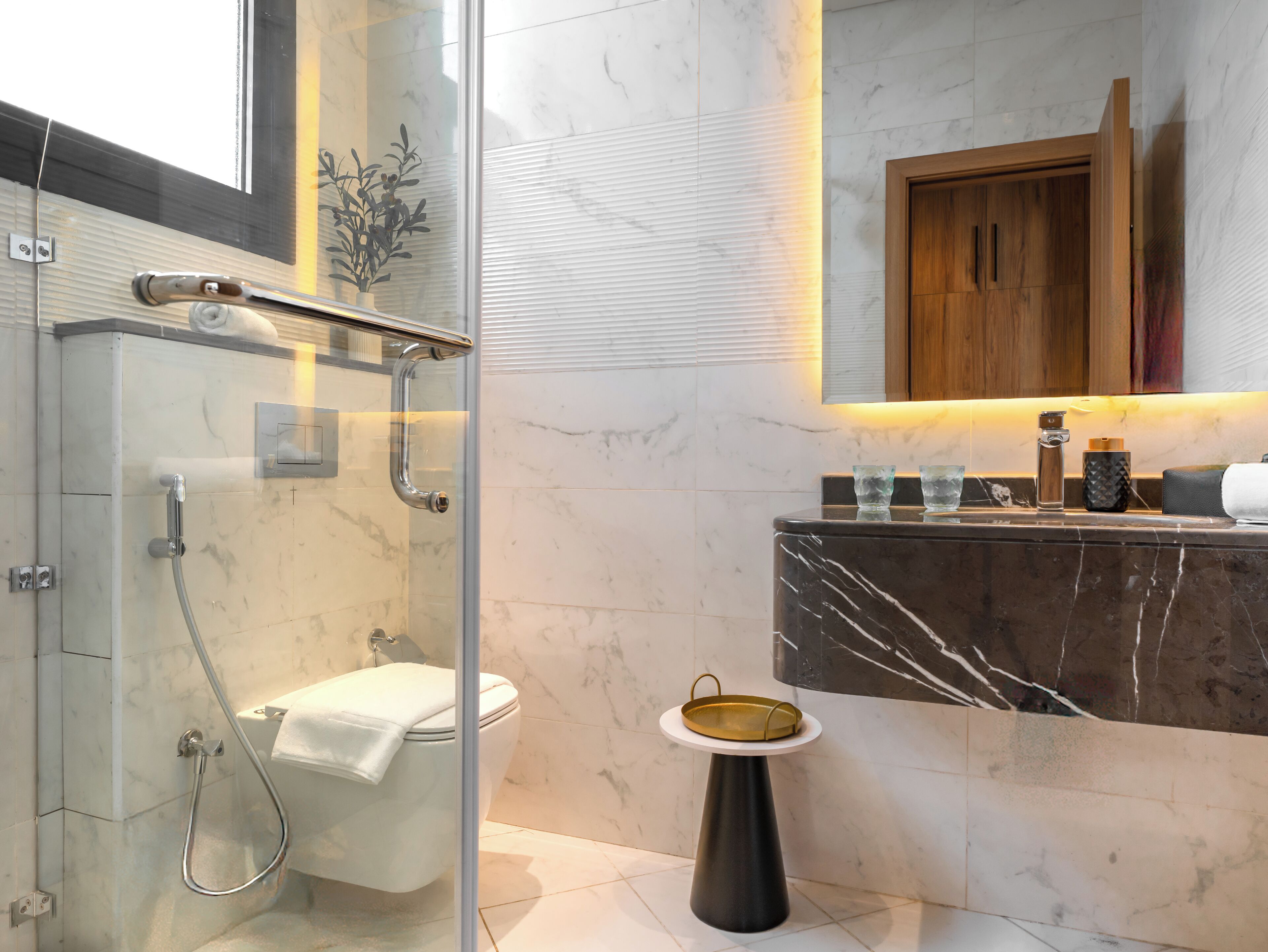 A modern bathroom with a glass-enclosed shower, a marble vanity, and a wooden cabinet above the sink.