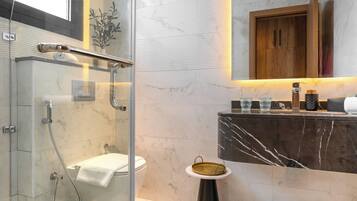 A modern bathroom with a glass-enclosed shower, a marble vanity, and a wooden cabinet above the sink.