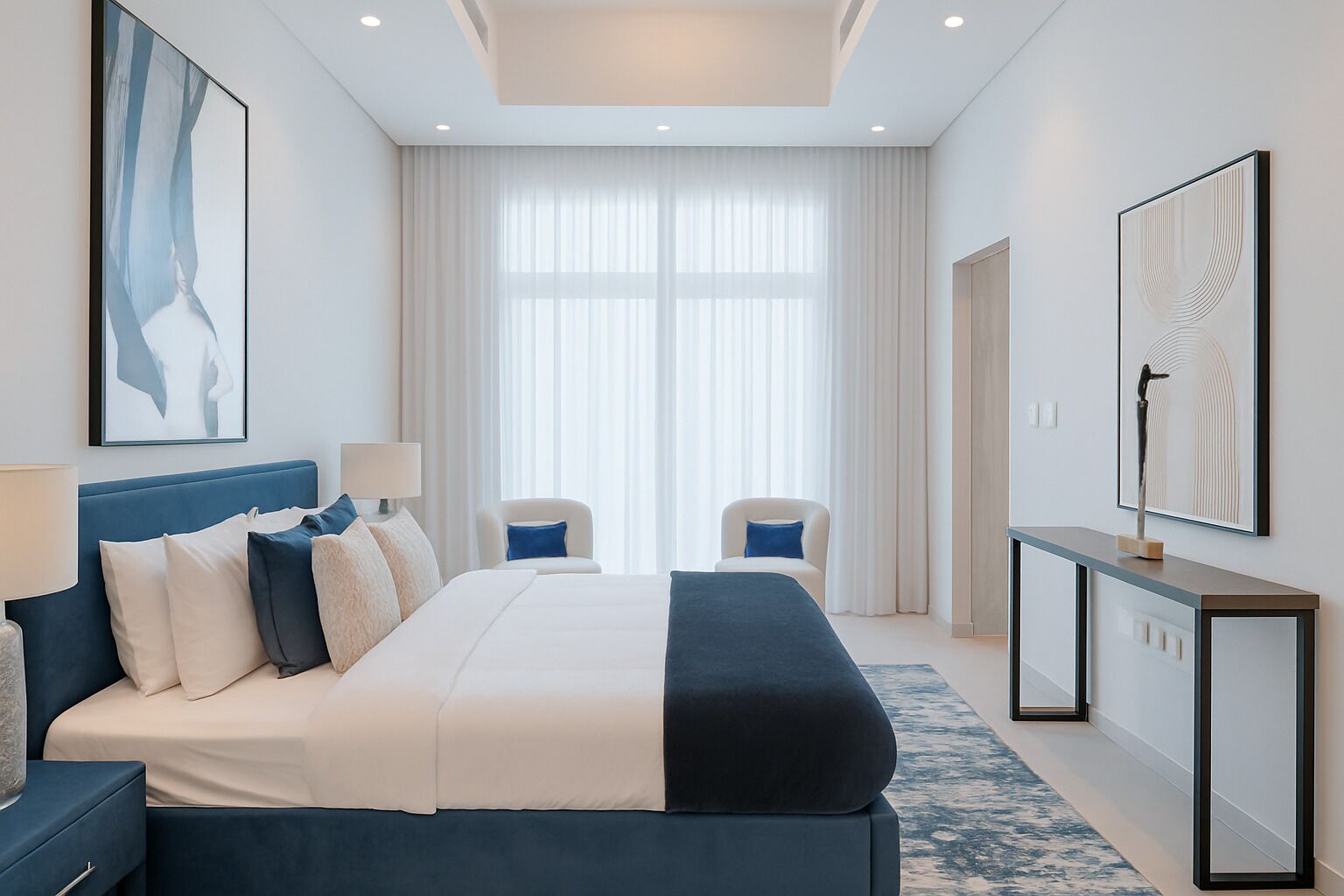 A modern hotel room with a large bed, two chairs, a desk, and artwork on the walls.
