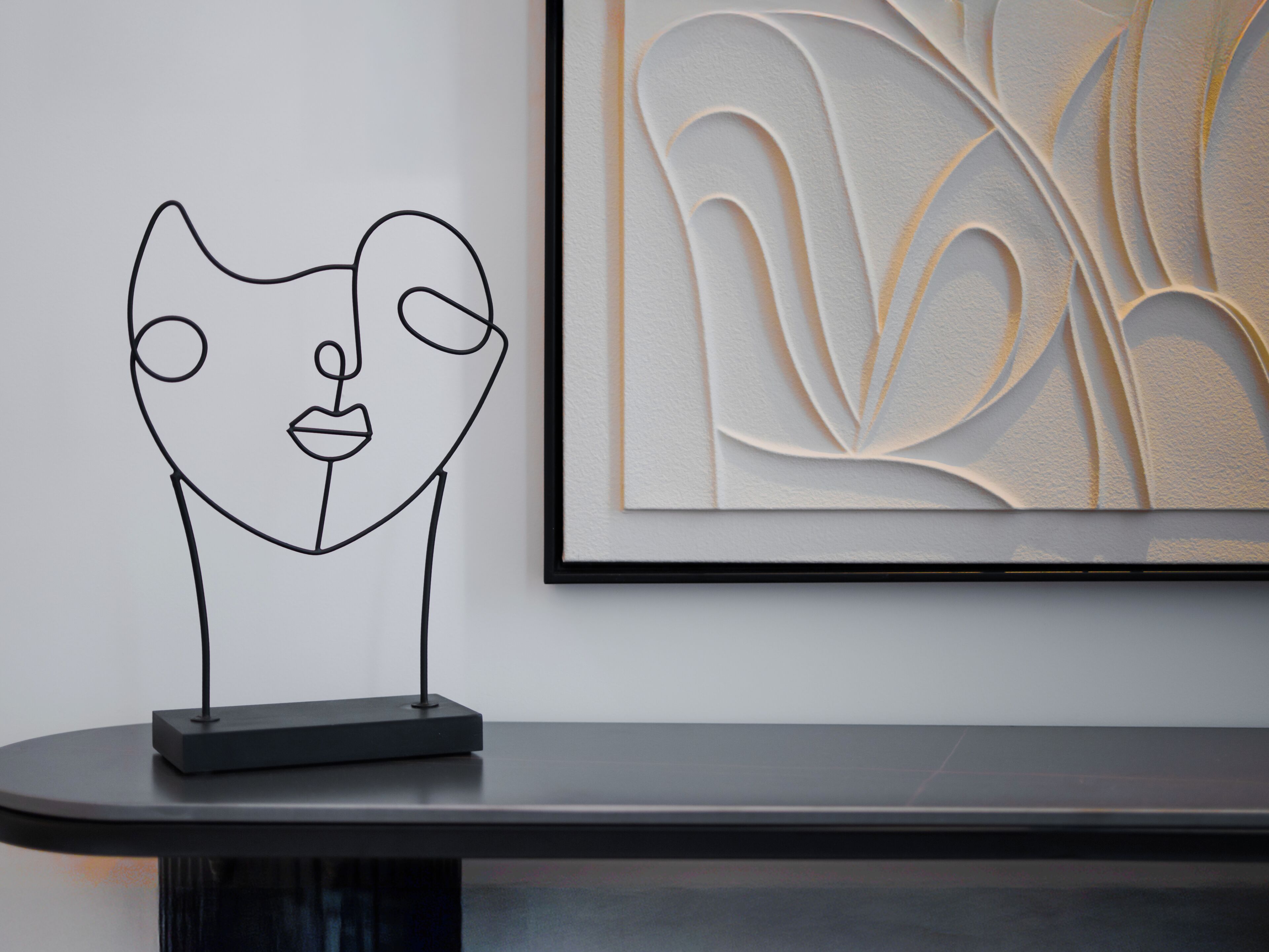 A minimalist art piece with a geometric design on a wall, a framed artwork with abstract patterns, and a sleek, modern table.