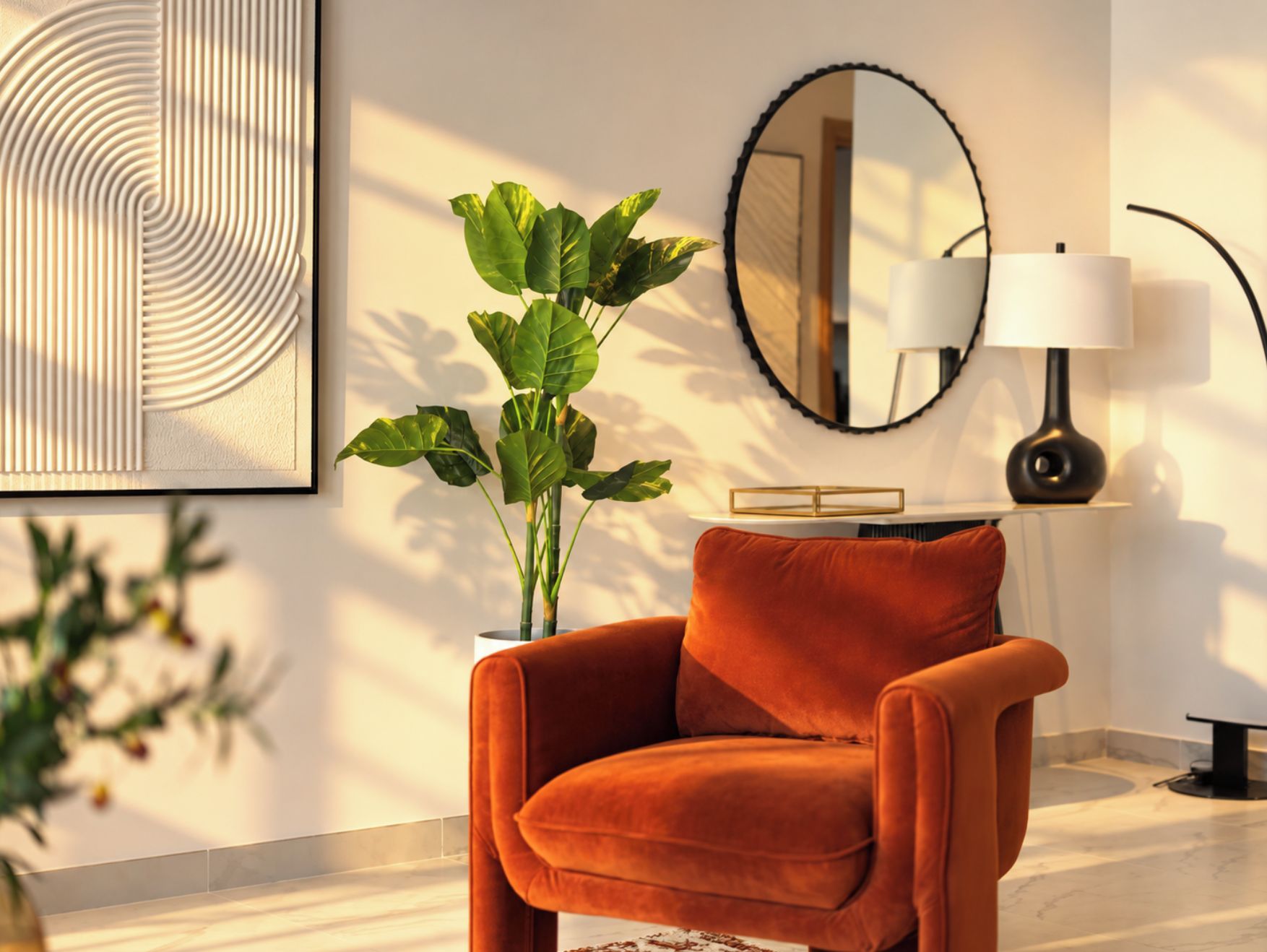 A modern living room with a plush orange chair, a large green plant, a round mirror, and a table with a lamp.