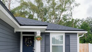 Una casa residencial con puerta principal azul oscuro, detalles blancos y un pequeño porche.