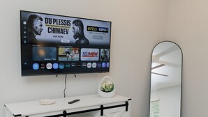 Un mueble blanco de entretenimiento con un televisor montado mostrando la interfaz de un servicio de streaming.