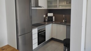 A compact kitchen with a refrigerator, microwave, oven, and a sink. - Apartment  Vitamina & Sea, Mil Palmeras, Torre de la Horadada (Torre de la Horadada)