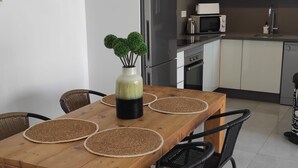 A dining area with a wooden table, woven placemats, black chairs, and a potted plant. - Apartment  Vitamina & Sea, Mil Palmeras, Torre de la Horadada (Torre de la Horadada)