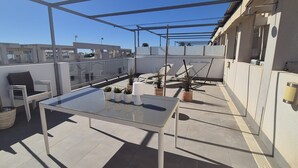 A rooftop terrace with a glass table, chairs, potted plants, and a pergola structure. - Apartment  Vitamina & Sea, Mil Palmeras, Torre de la Horadada (Torre de la Horadada)