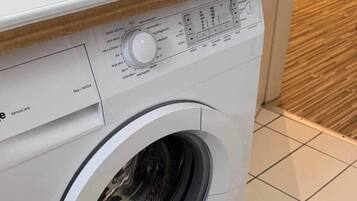 Voorweergave van een witte wasmachine met bedieningspaneel en een label met de tekst 'Sensocare'.