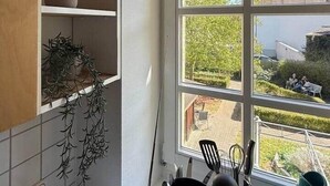 Een keuken met een raam, een koffieapparaat en een hangplant.
