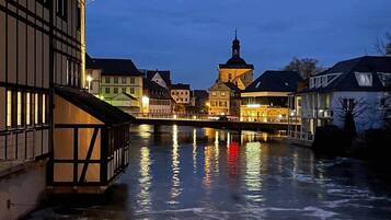A nighttime view of a riverside town with buildings reflecting on the water.