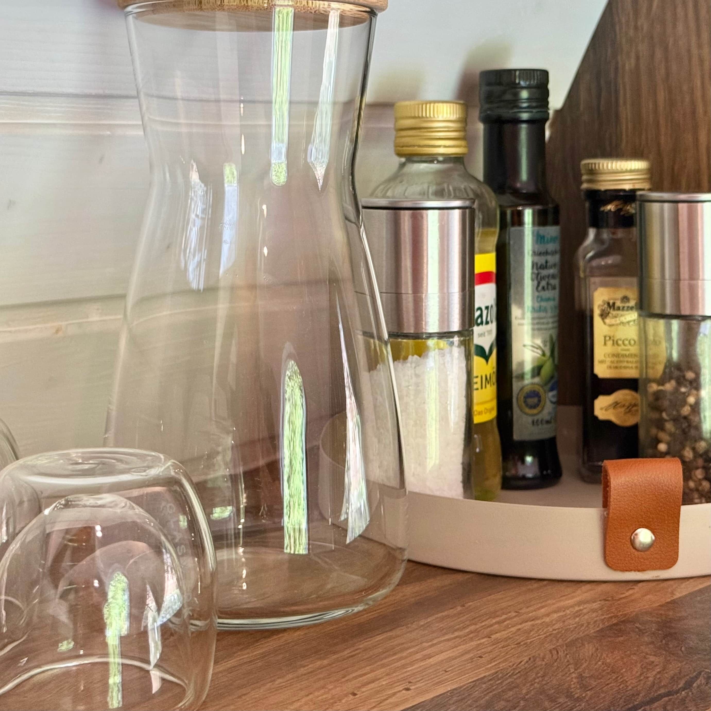 Eine Küchenarbeitsplatte mit einer Glas-Kaffeekanne, einer Olivenölfiole und verschiedenen Gewürzflaschen.