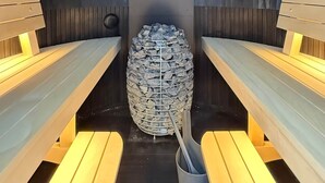 A sauna with benches and a central stone structure. - Iglu – Chestnut (Frensdorf)