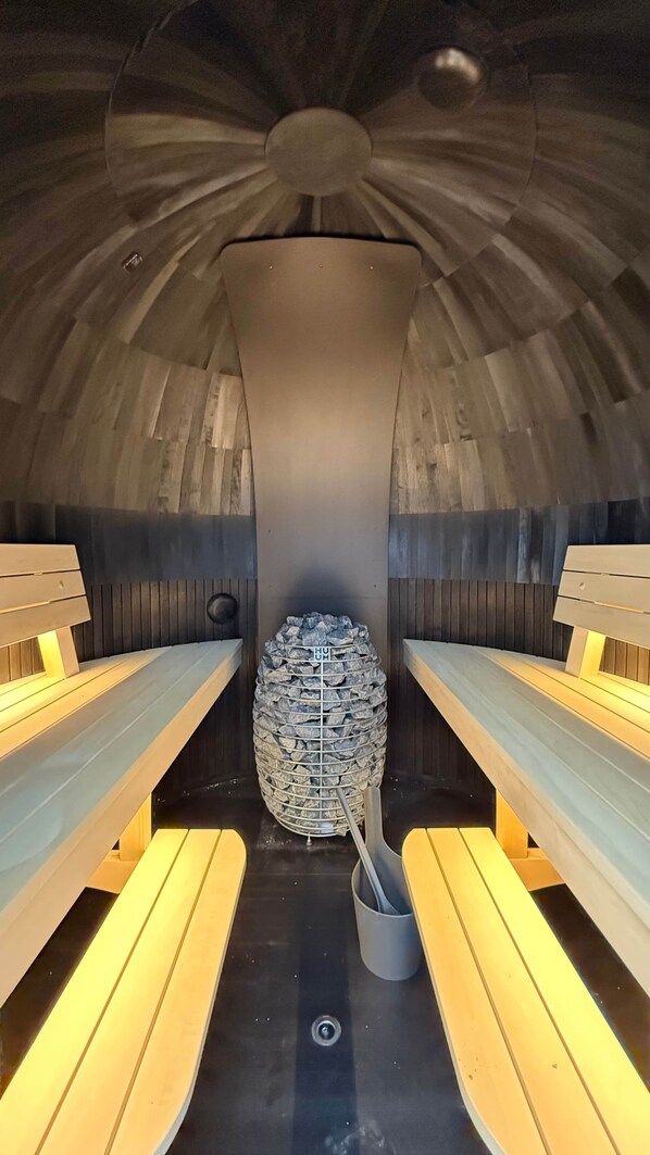 A sauna with benches and a central stone structure.
