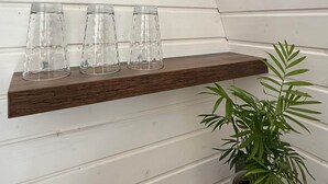 A corner with two wooden shelves against a white paneled wall, each holding clear glass cups and a potted plant. - Iglu – Chestnut (Frensdorf)
