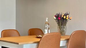 A dining table with four chairs, a vase with flowers, and a pendant light. - Pretty City - Tiny Apartment Bamberg (Bamberg)