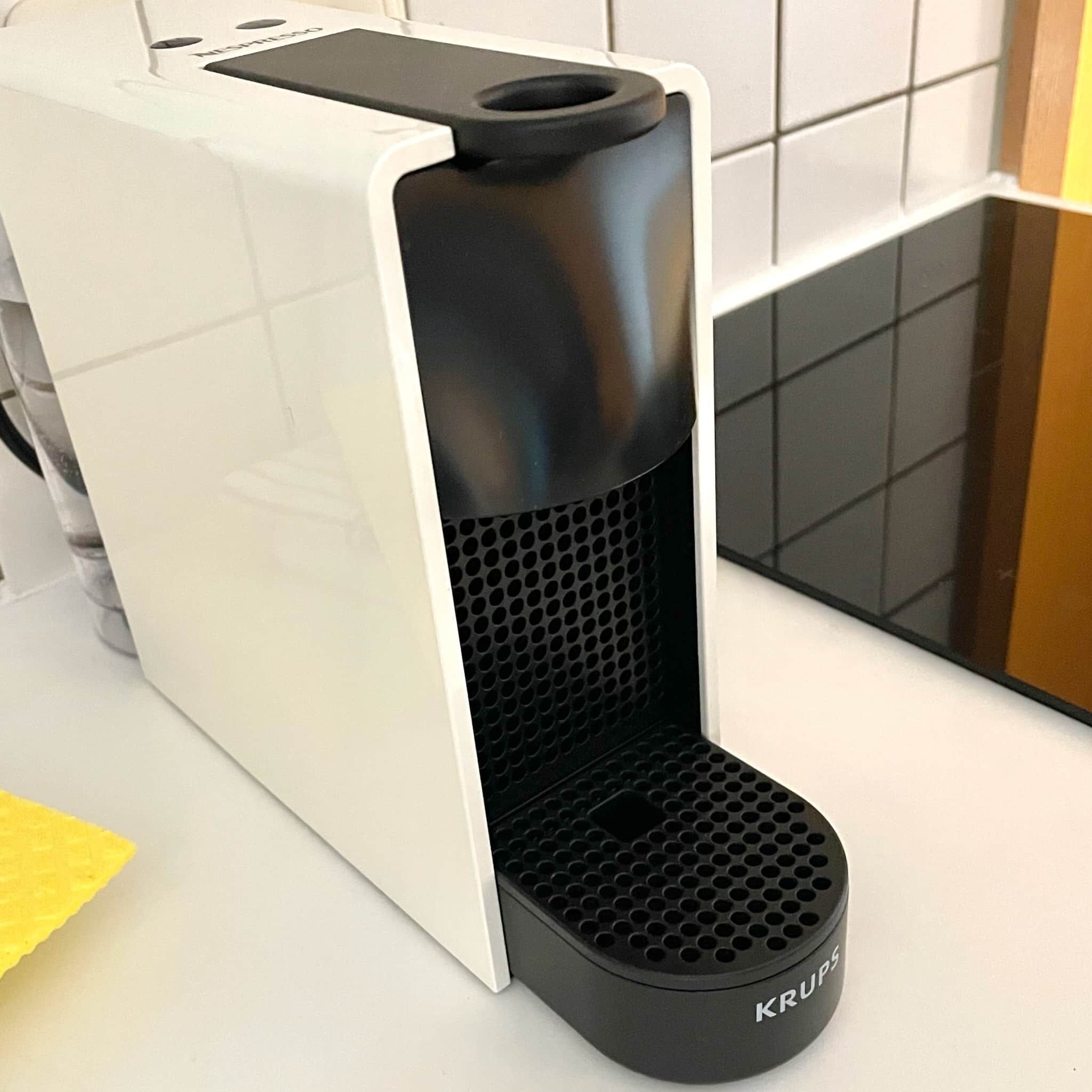 A Krups coffee maker with a white and black design, placed on a kitchen counter.