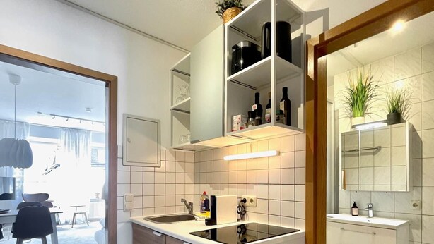 A modern kitchen with a central island, white cabinetry, and a built-in oven. - Pretty City - Tiny Apartment Bamberg (Bamberg)