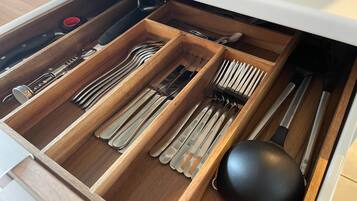A drawer with multiple compartments containing various utensils like forks, knives, and spoons.