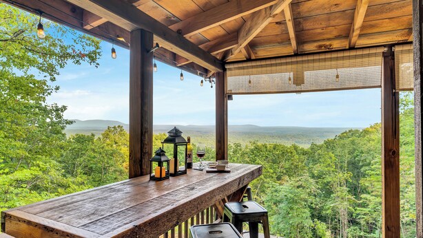 Una terraza de madera con mesa y sillas que da a un paisaje boscoso.