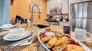Una cocina con gabinetes blancos, electrodomésticos de acero inoxidable y una mesa de desayuno en la encimera.