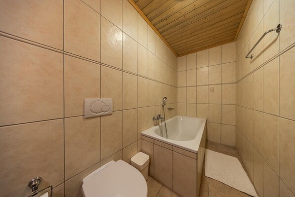 A bathroom with a bathtub, toilet, and a towel rack.