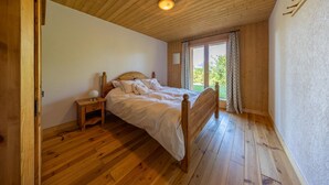 Een slaapkamer met een houten bed, een nachtkastje en een raam met gordijnen.