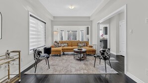 A living room with a sectional sofa, two patterned chairs, a coffee table, and a rug. - 100% Private and Spotless ~Fresh Linens ~New House (Thorold)